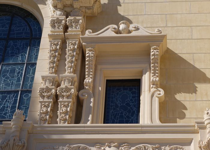 Highly detailed cast stone window surround with decorative pilasters and carved ornament