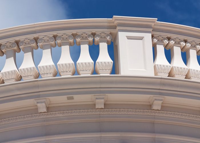 Curved cast stone balustrade with ornamental balusters against blue sky